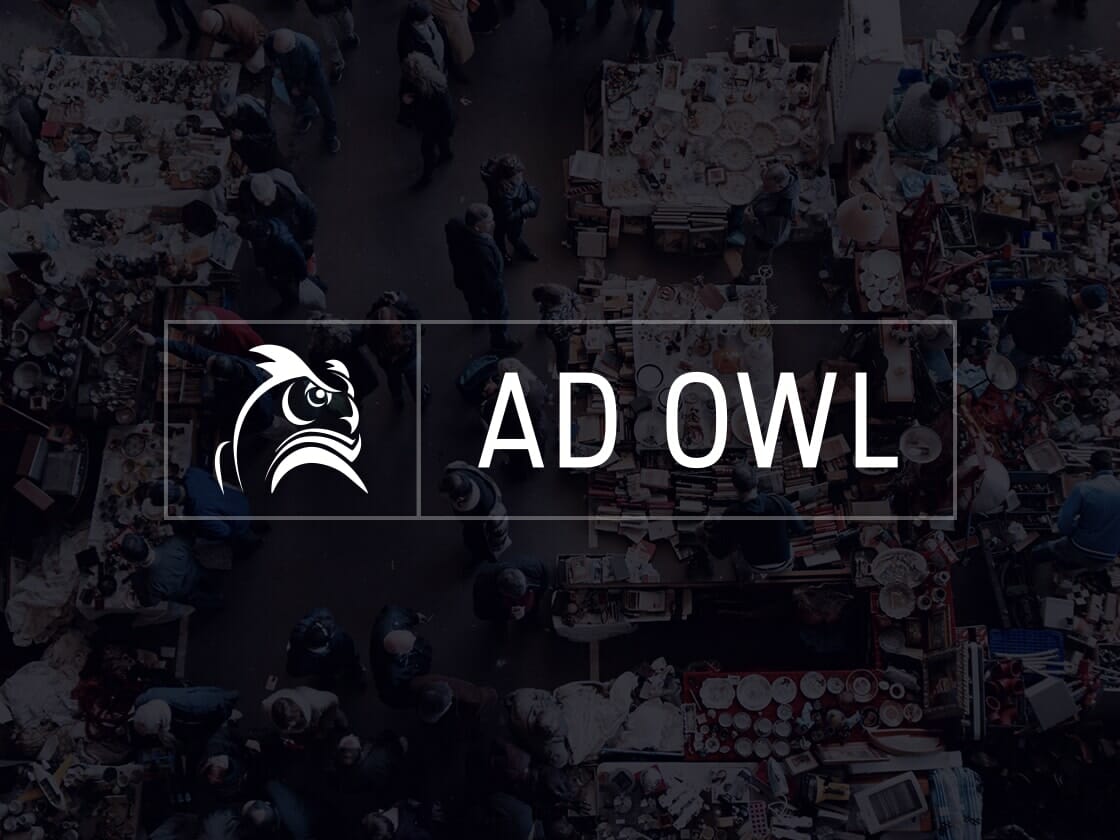 A busy marketplace with numerous stalls and people seen from above. The scene is slightly blurred and overlaid with a transparent dark layer. At the center of the image, there's a logo of an owl's head and the text "AD OWL" displayed in white capital letters within a rectangular border.