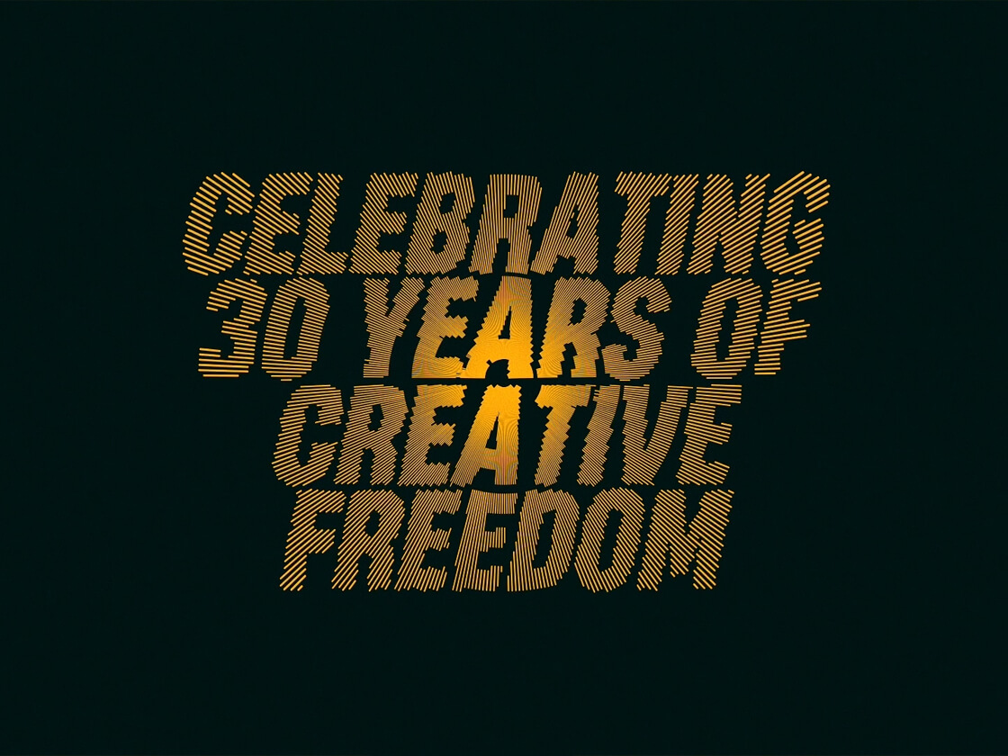 Celebrating 30 Years of Creative Freedom" is written in bold, yellow, diagonal striped text against a dark green background, with a glowing effect behind the words in a looped video that captures the essence of Basha Uhuru.