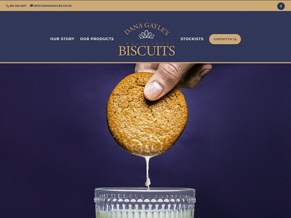 A person dipping a large biscuit into a glass of milk against a purple background on Dana Gayle's website.