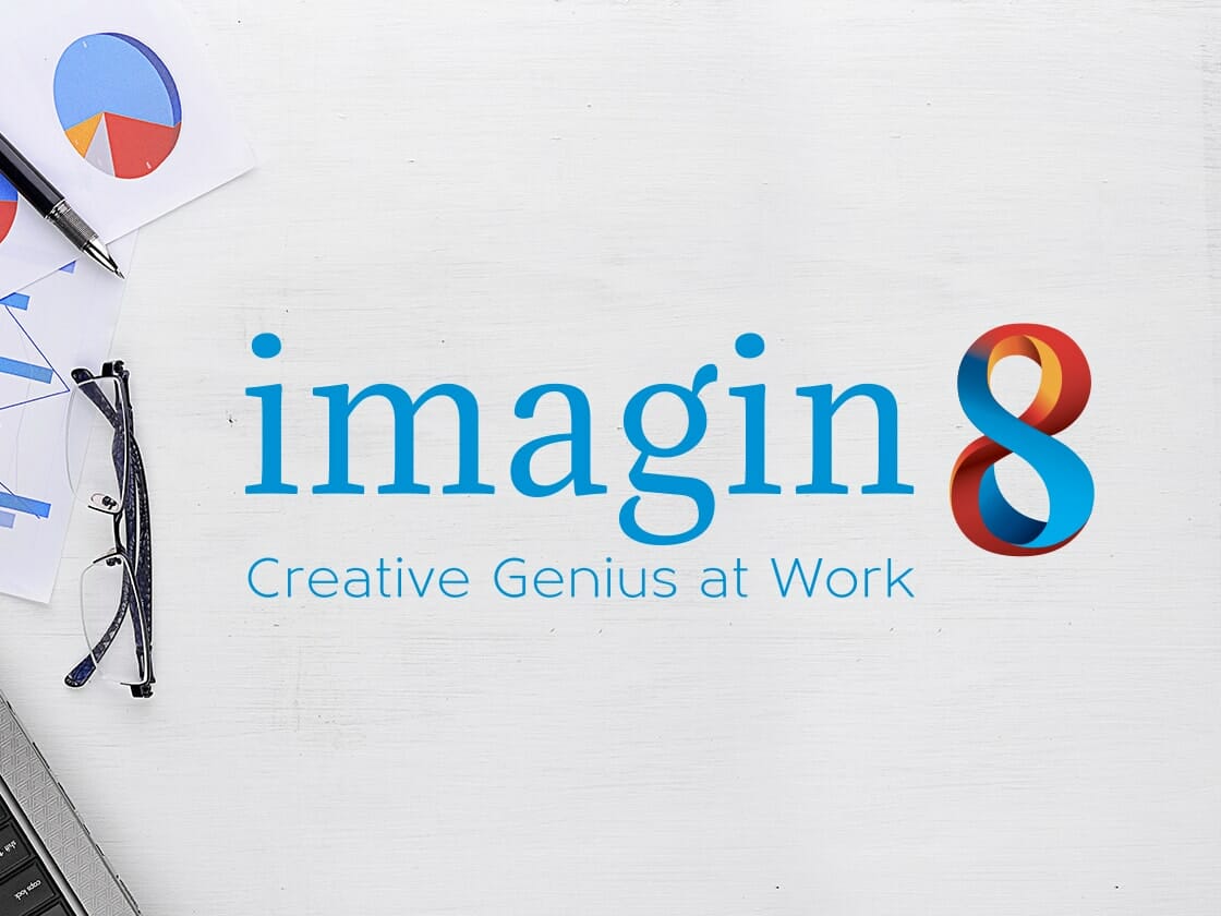 A desktop scene with a white background displaying the company name "imagin8" in large blue text, followed by the tagline "Creative Genius at Work" in smaller blue text. To the left are glasses, a pen, and sheets with pie charts. The "8" in "imagin8" has a colorful, ribbon-like design.