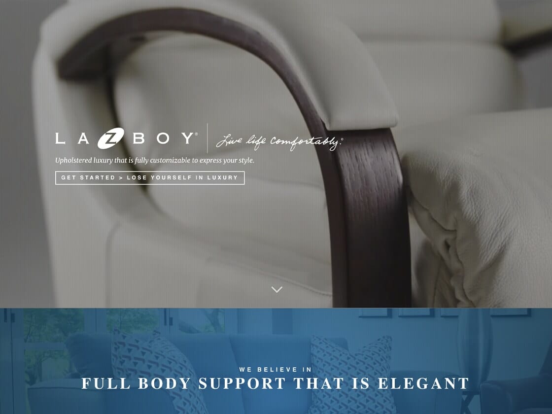 Image of the La-Z-Boy website homepage featuring a close-up of an armchair with a wooden armrest and cream-colored upholstery. Text over the image reads: "Live life comfortably." Below, there is a section with sofas and chairs in a living room, and the text: "We believe in full body support that is elegant.