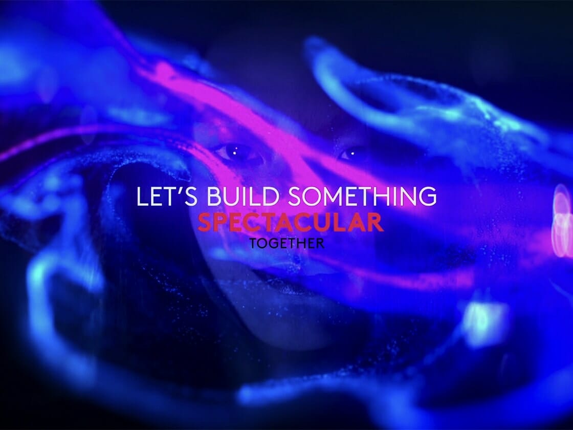 A dynamic and colorful abstract video with the motivational slogan "let's build something spectacular together" displayed prominently.