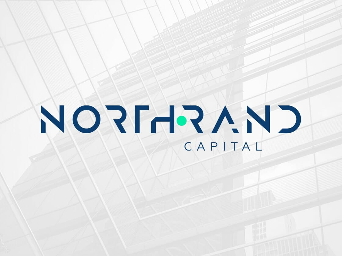 The image features the logo of Northrand Capital with modern, stylized blue text on a transparent background. "NORTHRAND" is in capitals with a green dot between "H" and "R," and "CAPITAL" in smaller font below. The backdrop reveals the exterior of a sleek glass building, complementing the company's logo perfectly.