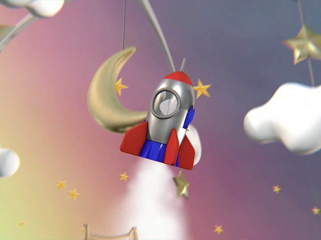 An animated rocket ship with red fins and a blue body flies in a whimsical night sky scene. The backdrop features a crescent moon, stars, and fluffy clouds against a gradient purple and pink sky. The rocket emits white smoke as it ascends, adding motion to the imaginative illustration.