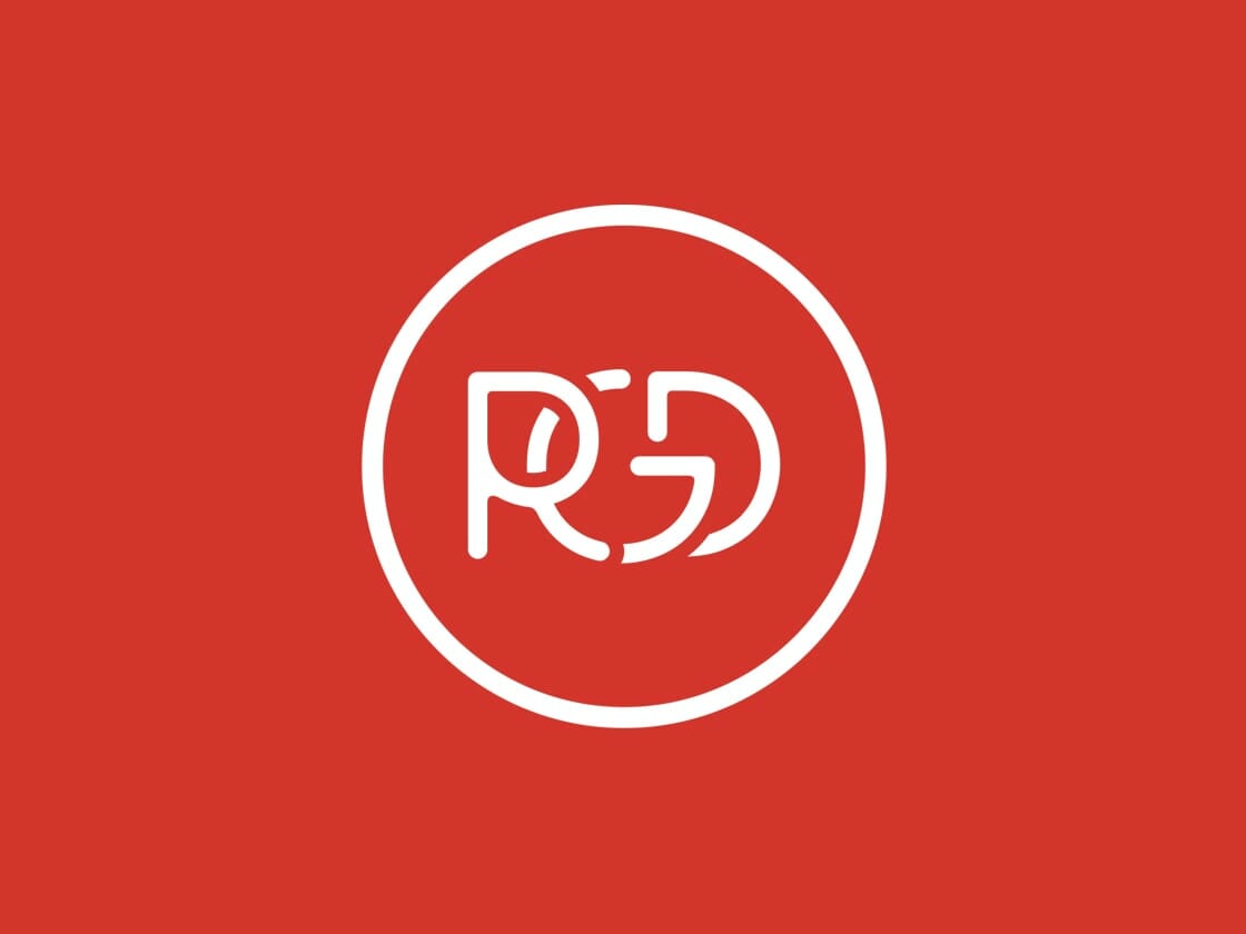 A white circular logo on a red background features the stylized letters "RGD" in the center, with unique font. The design within the circle incorporates the letters seamlessly, creating an abstract and modern appearance. The red and white color scheme is bold and eye-catching.