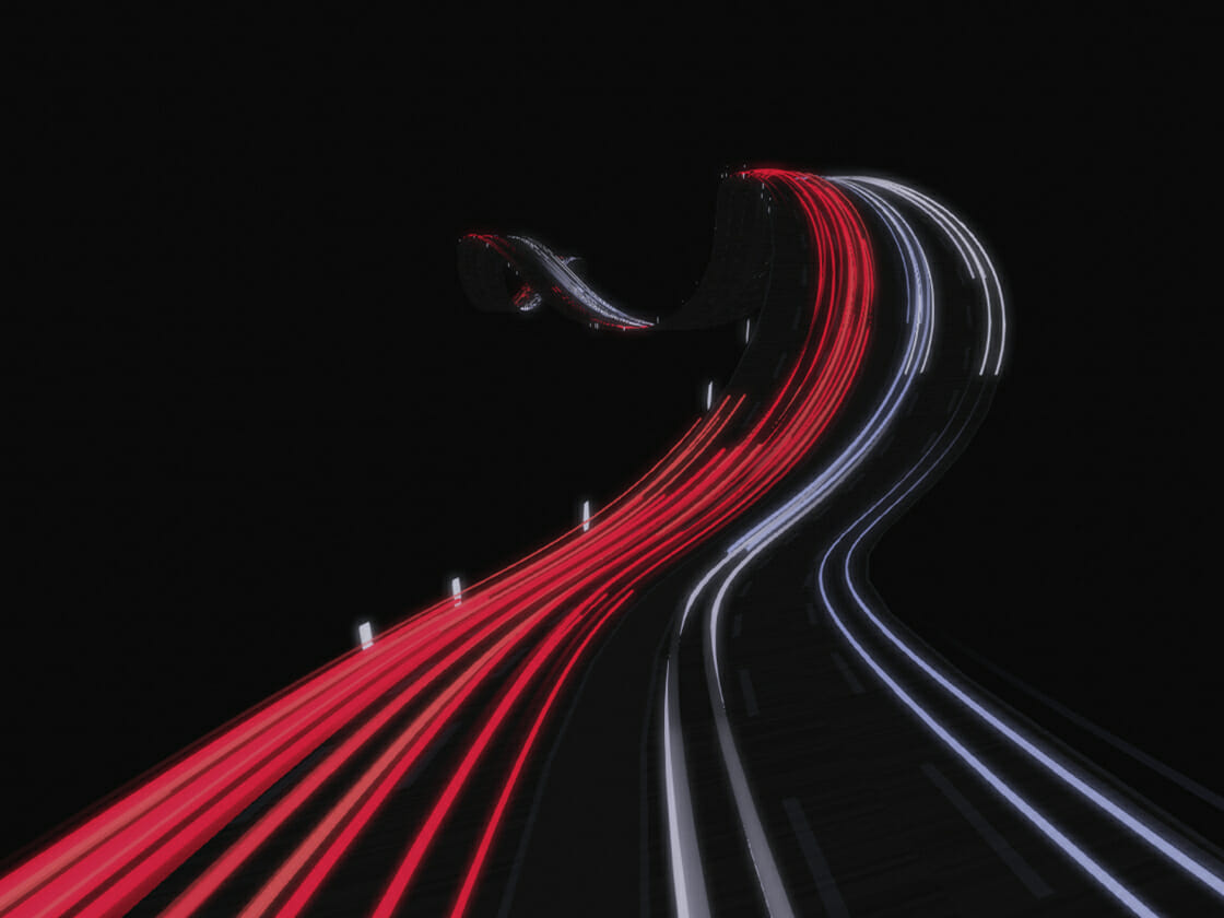 Long exposure of a highway at night capturing the high-speed light trails of moving vehicles.