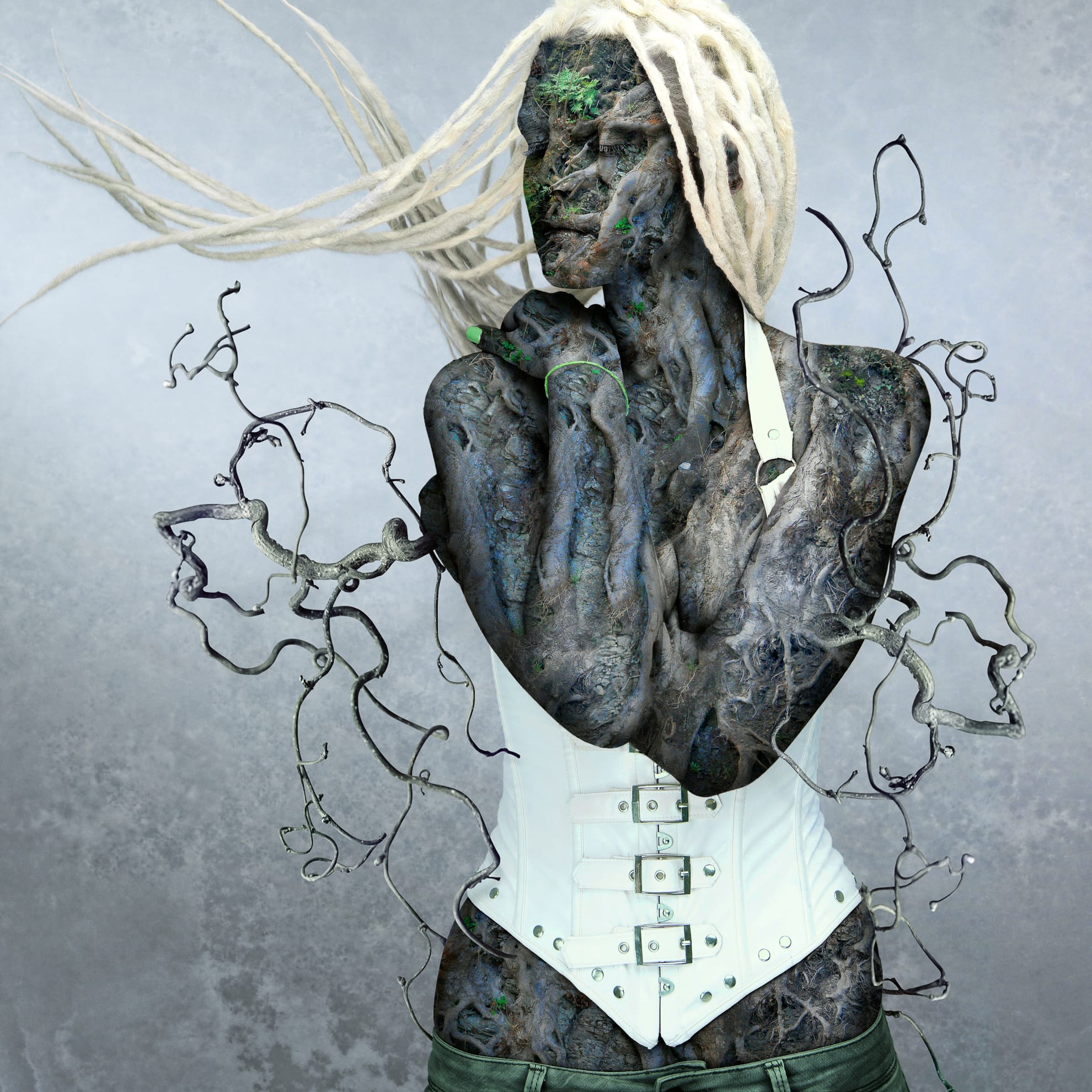 A fantastical being with skin resembling dark tree bark has long, white dreadlocks flowing sideways. The figure wears a white corset and green lower garments. Twisted branches extend from their arms, blending with their wooden appearance as if you reap what nature sows. The background is a foggy, gradient gray.