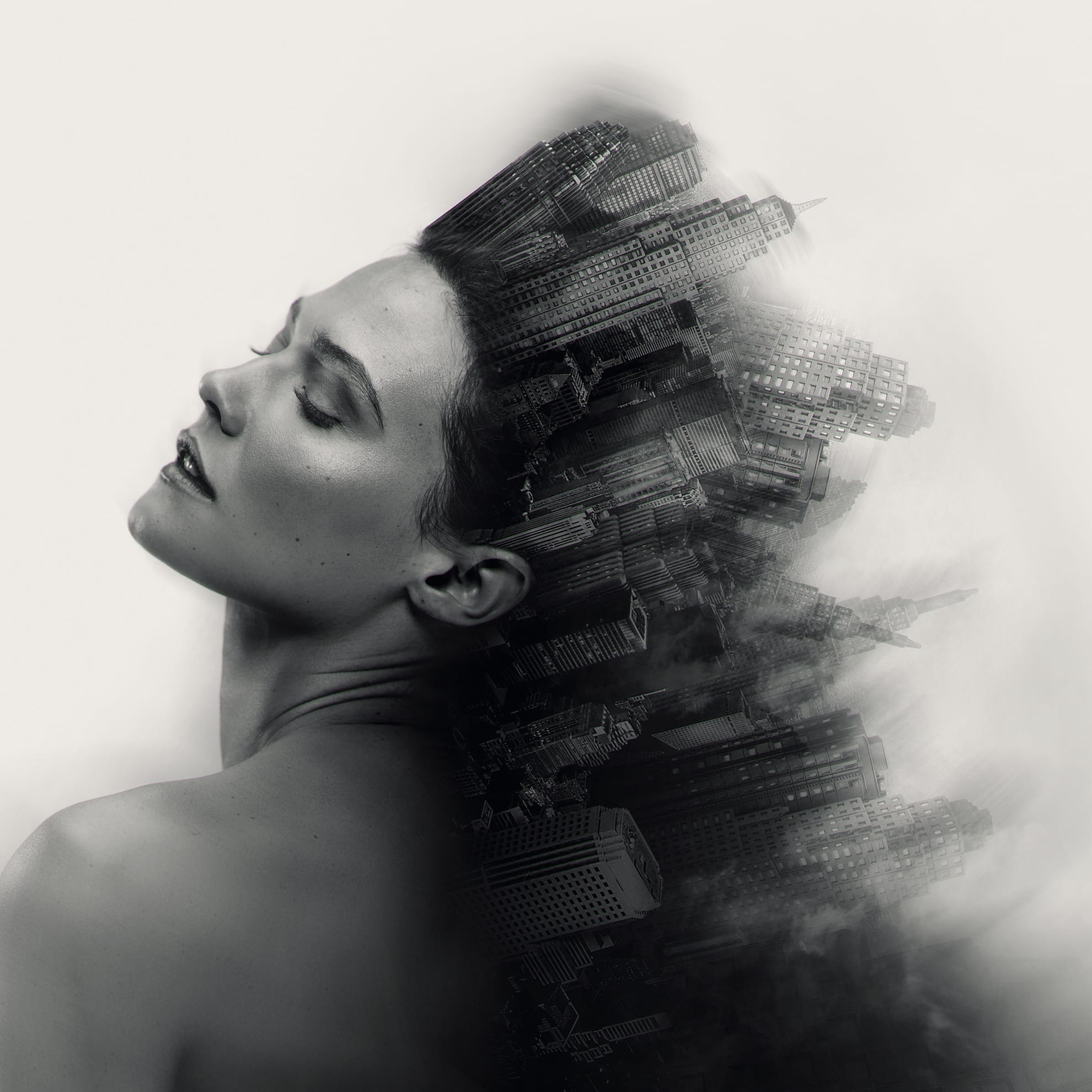 A black and white surrealistic image shows a woman's serene face and bare shoulders blending seamlessly into a skyline of tall buildings. The cityscape appears to emerge like a crown from her head, creating a fusion of human and urban elements, evoking a dreamlike, introspective atmosphere.