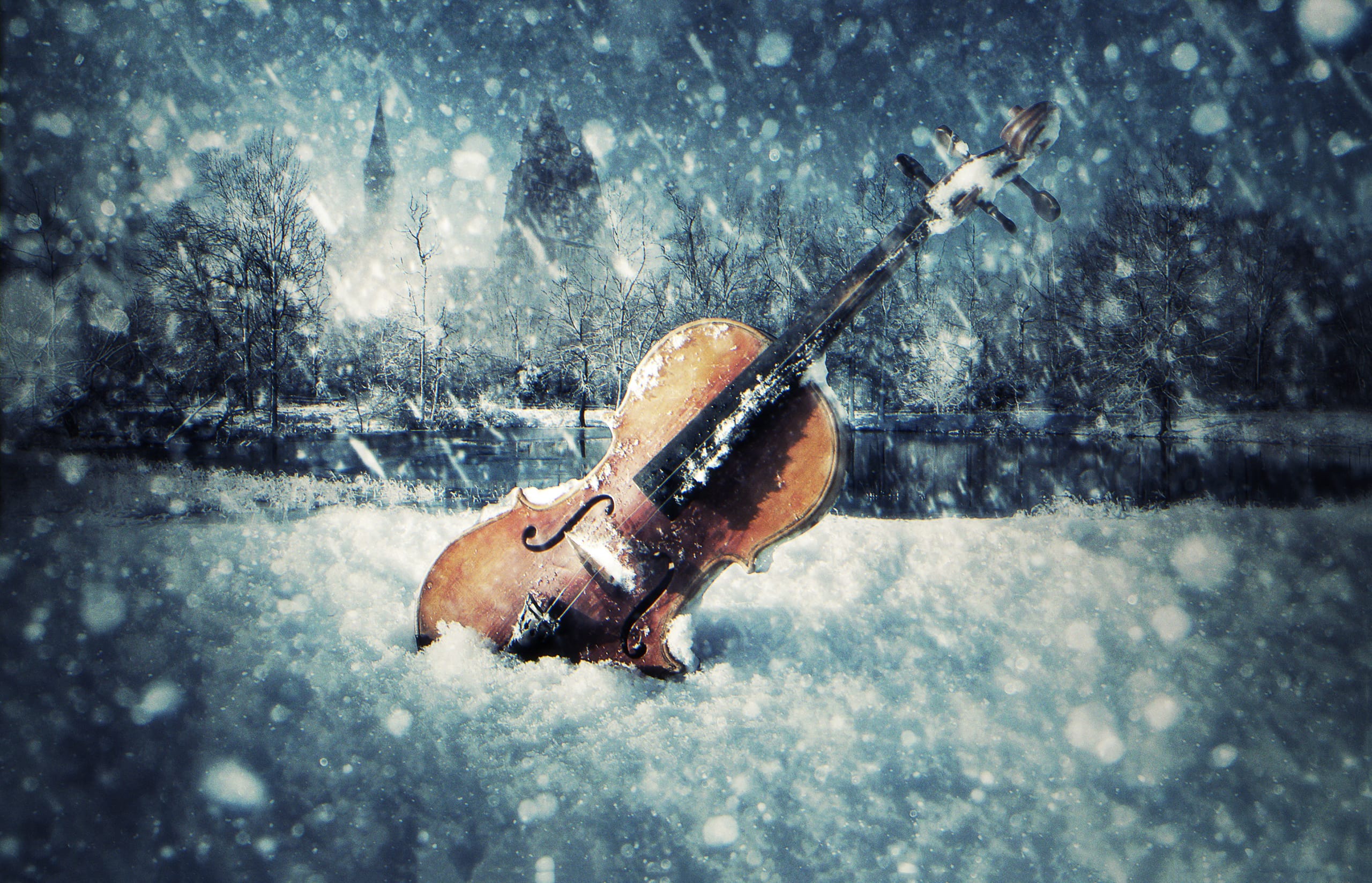 A cello stands upright in a snowy field, partially covered with snow. Snowflakes fall around it, and blurred trees are visible in the background, creating a serene winter scene. The image has an ethereal, almost magical feeling with the cello seemingly abandoned amidst the gentle snowfall, evoking a wistful tranquility.